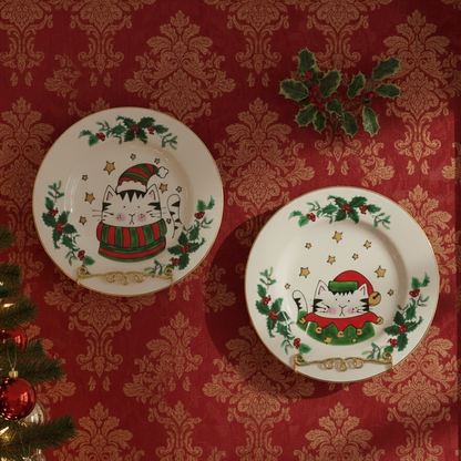 Two Christmas-themed plates with a cat design on a red wall with gold patterns.