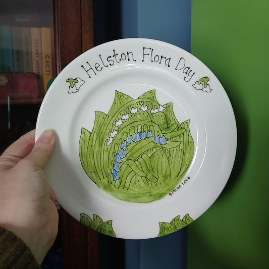 Hand holding a decorative plate with a green leaf design and text against a green background