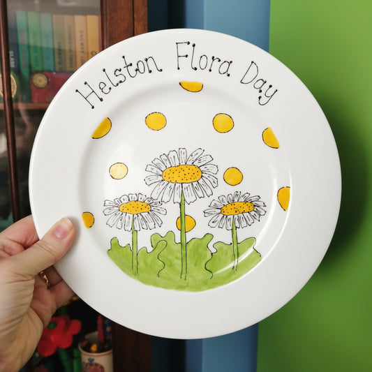 White plate with floral designs and text held by a hand against a green background