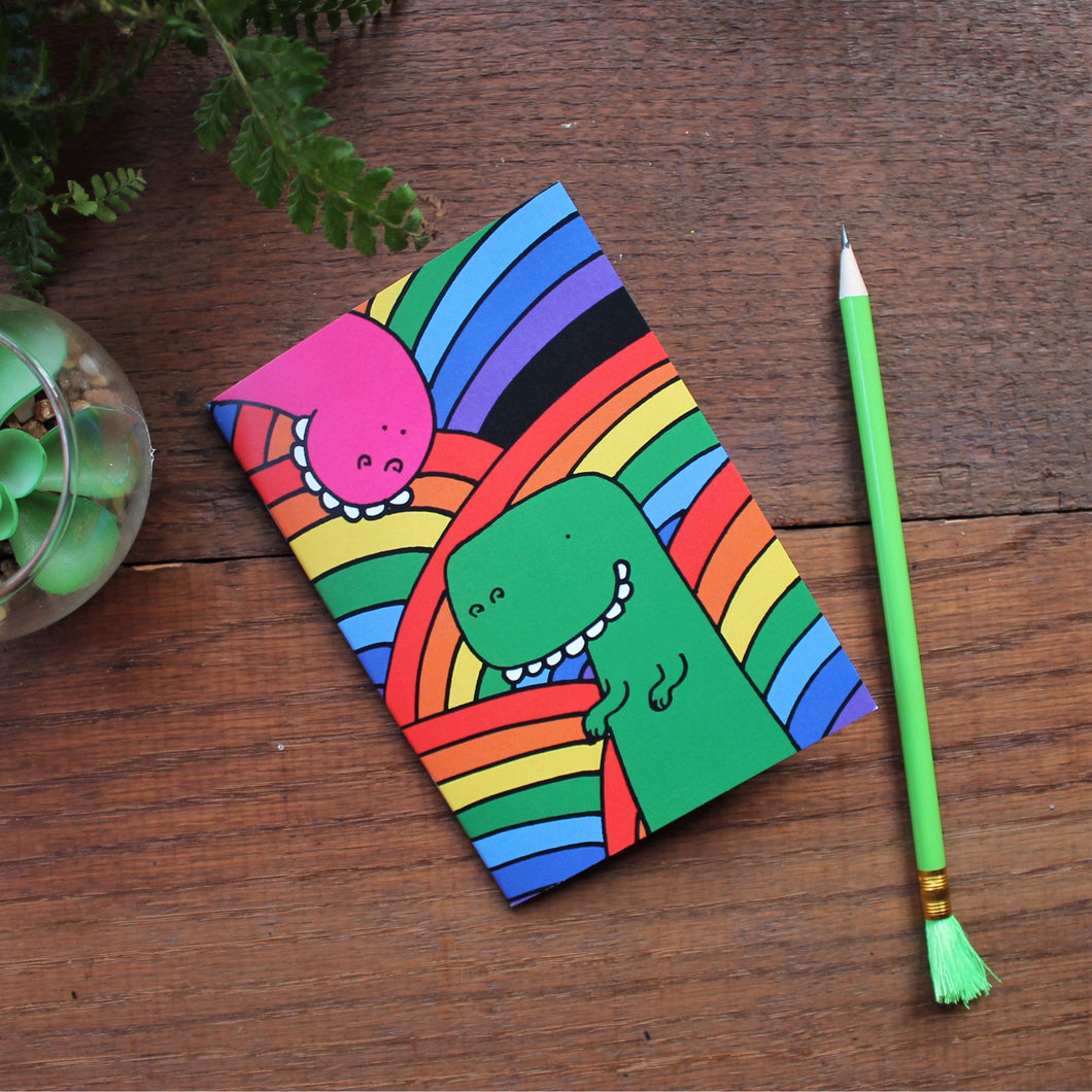Rainbow dinosaur notebook by Laura Lee designs goofy dinosaurs on a background of rainbows